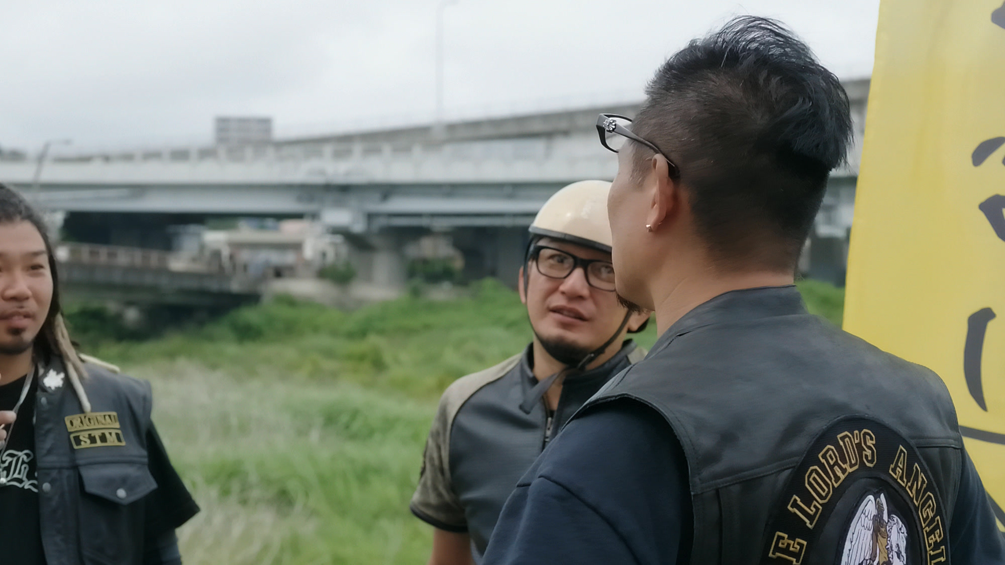 川沿いでチームエンブレムを背負って語り合うThe Lord's Angelsのメンバー