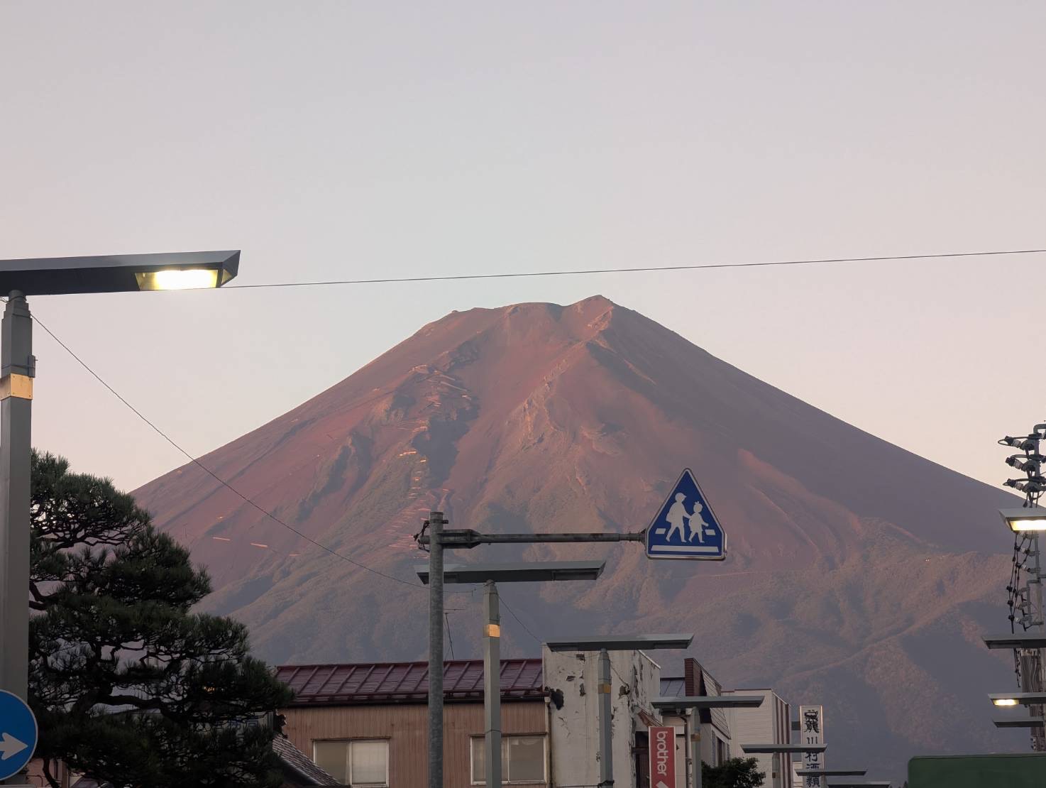 朝の街並みの向こうで赤く染まる富士山