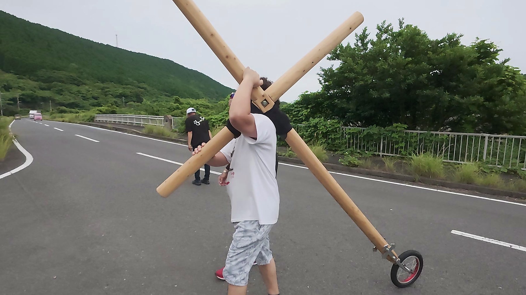 山あいの道を十字架を担いで歩く参加者