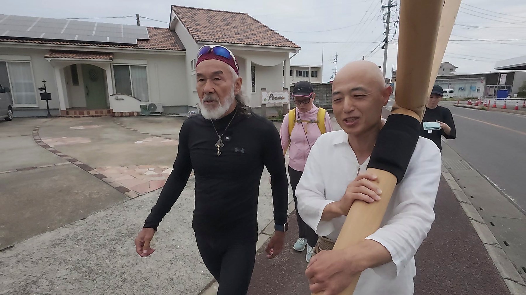 十字架を担ぐ参加者と並んで歩くアーサー先生