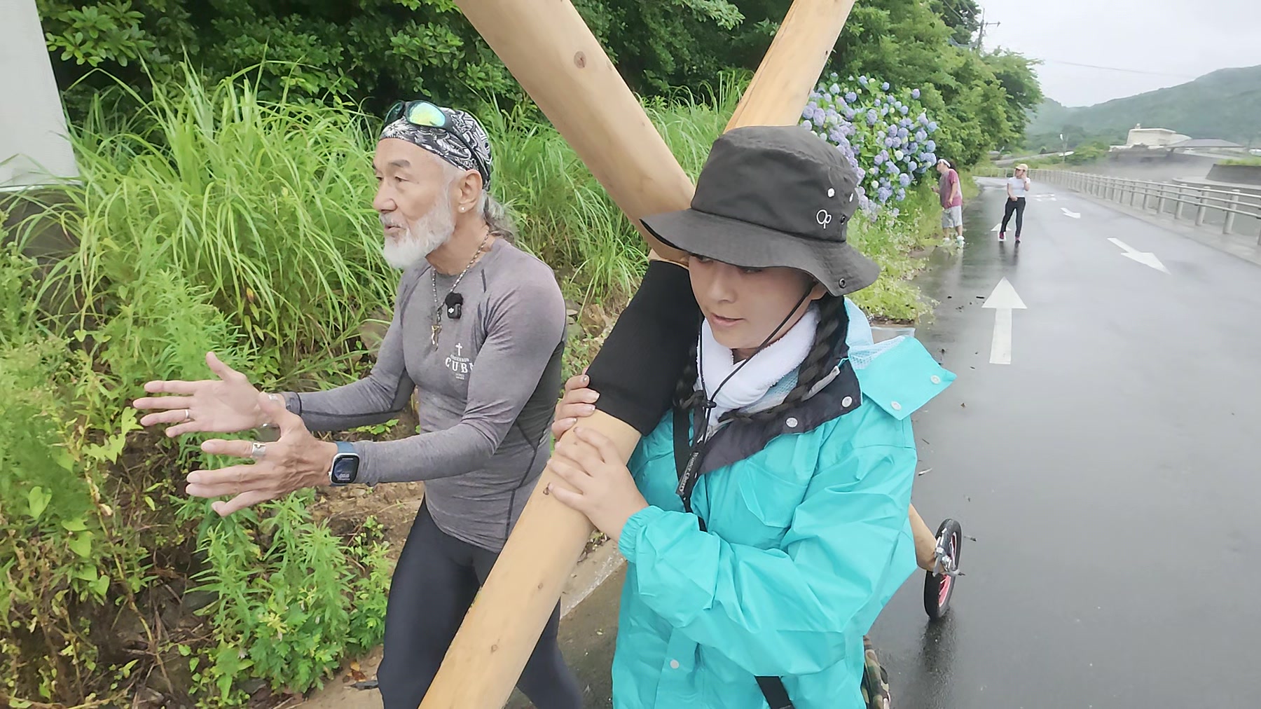 久賀島の海沿いの道で十字架を担いで歩くアーサー先生と参加者
