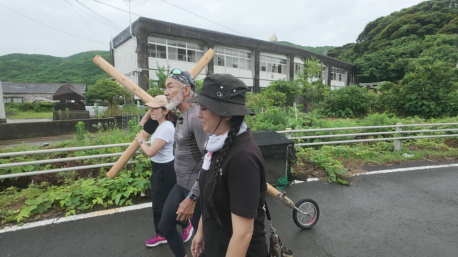 久賀島の集落のそばで十字架を担いで歩く参加者たち