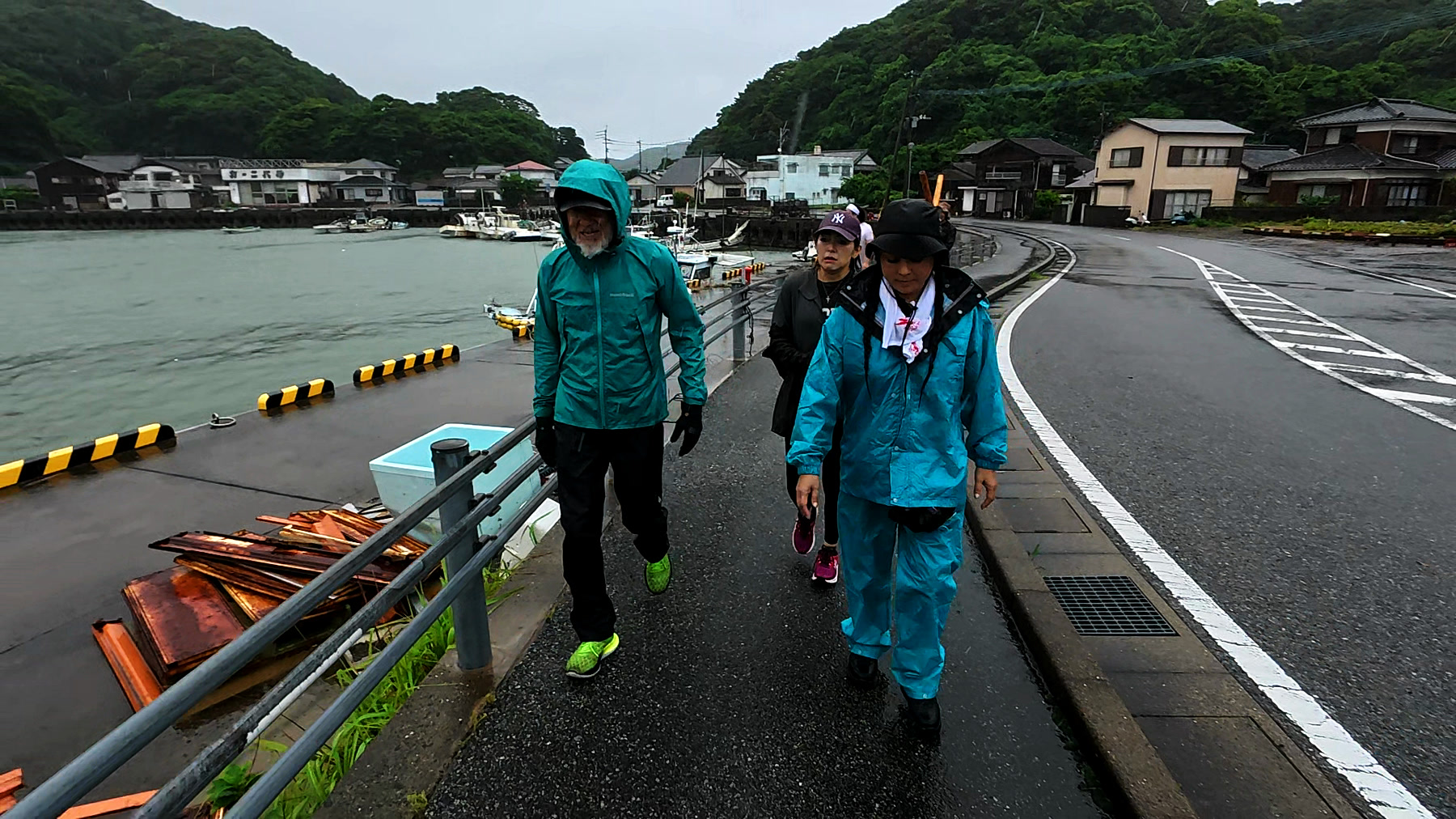奈留島の港沿いの道を歩くアーサー先生と参加者たち