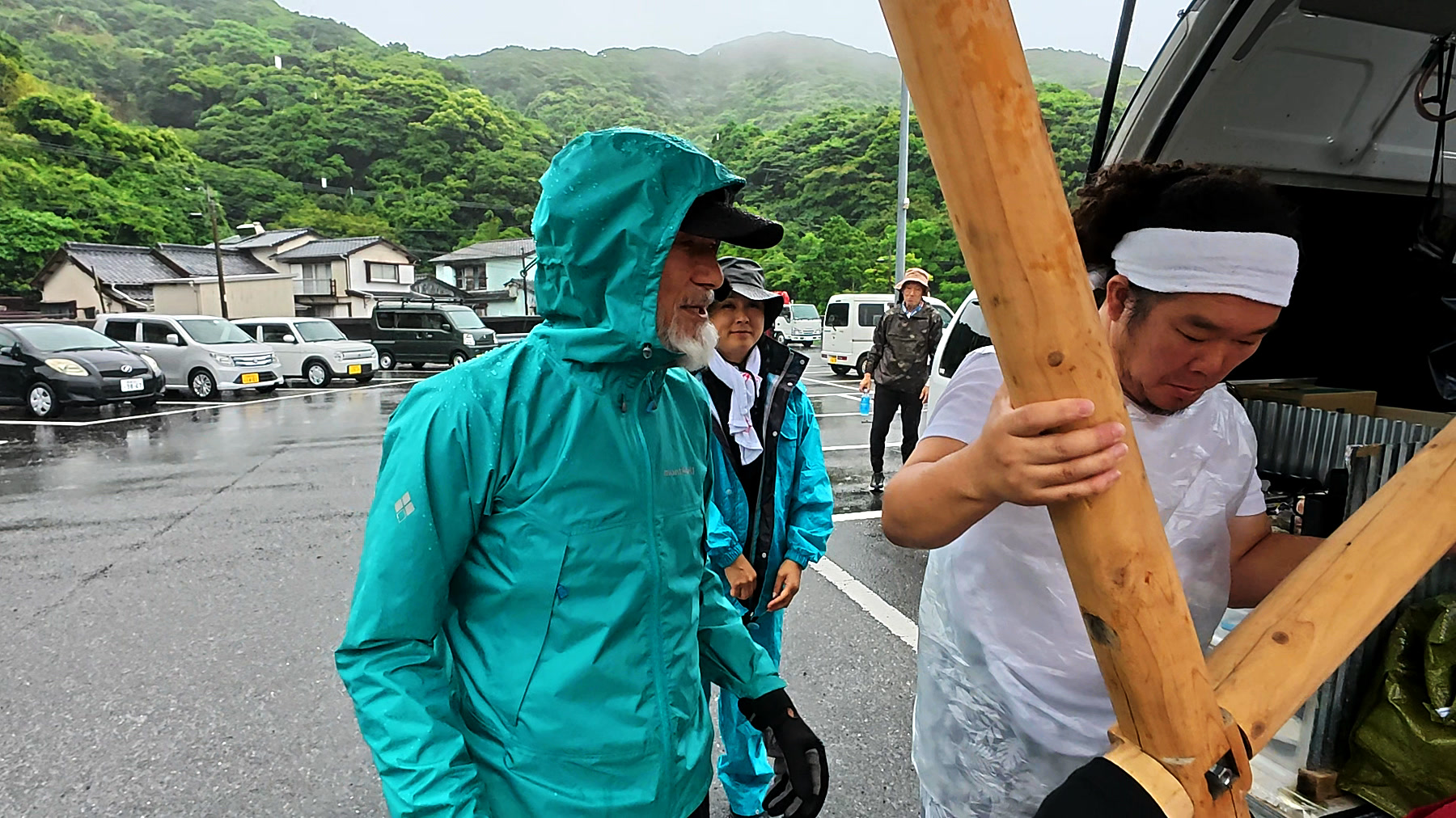 奈留島で十字架を組み、雨の中で行進を始めるアーサー先生と参加者