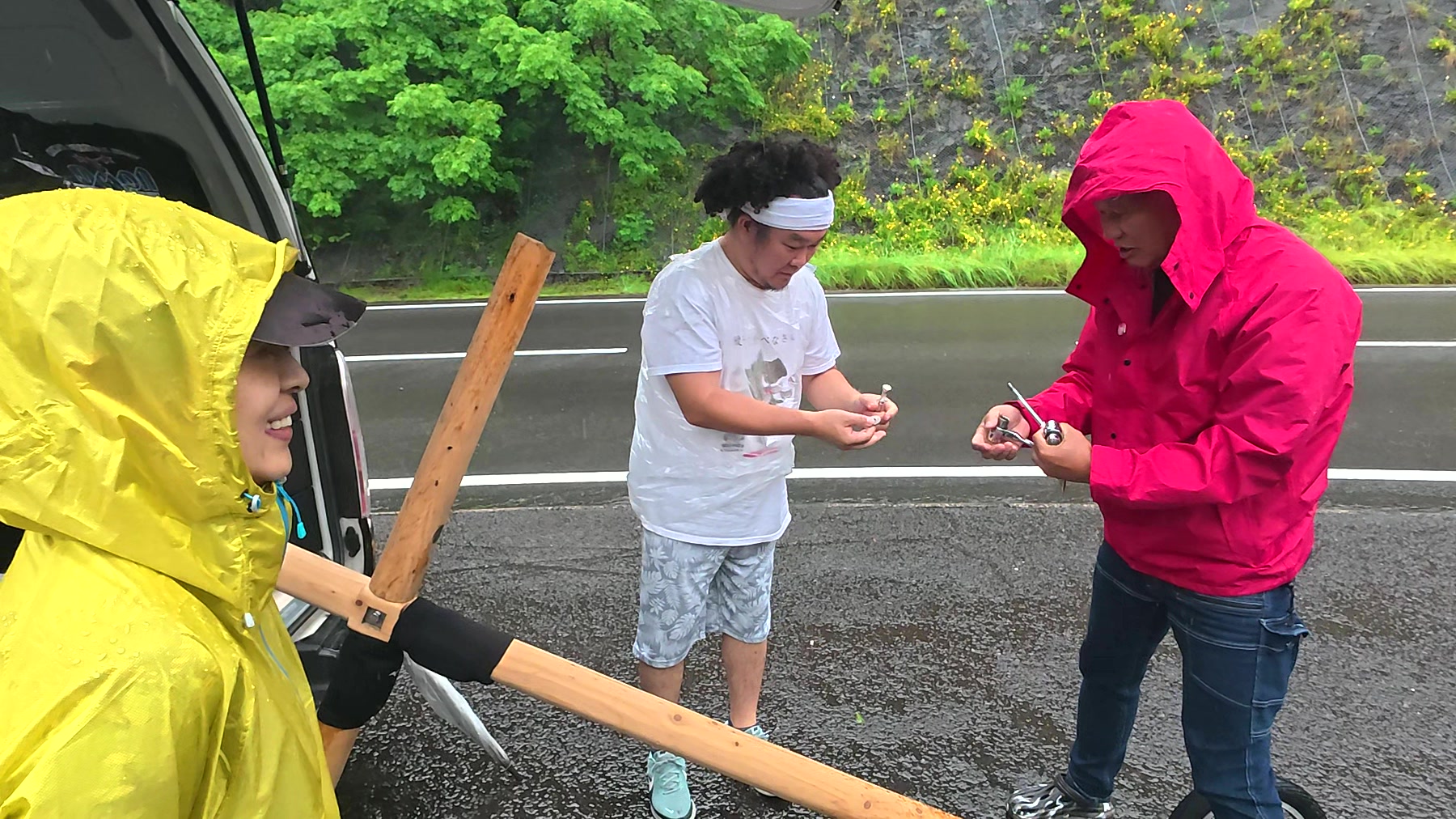 雨の中で十字架を組み立てるアーサー先生と参加者たち
