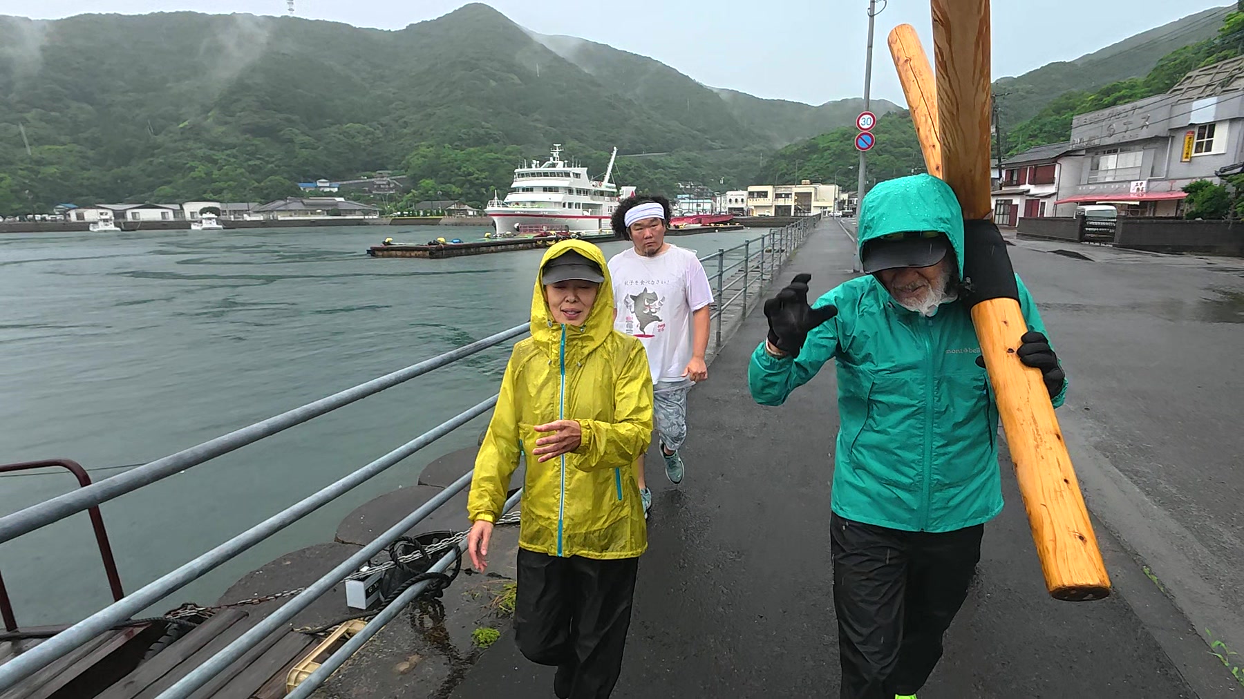 五島列島十字架行進5日目、上五島の港沿いで十字架を担いで歩く参加者たち