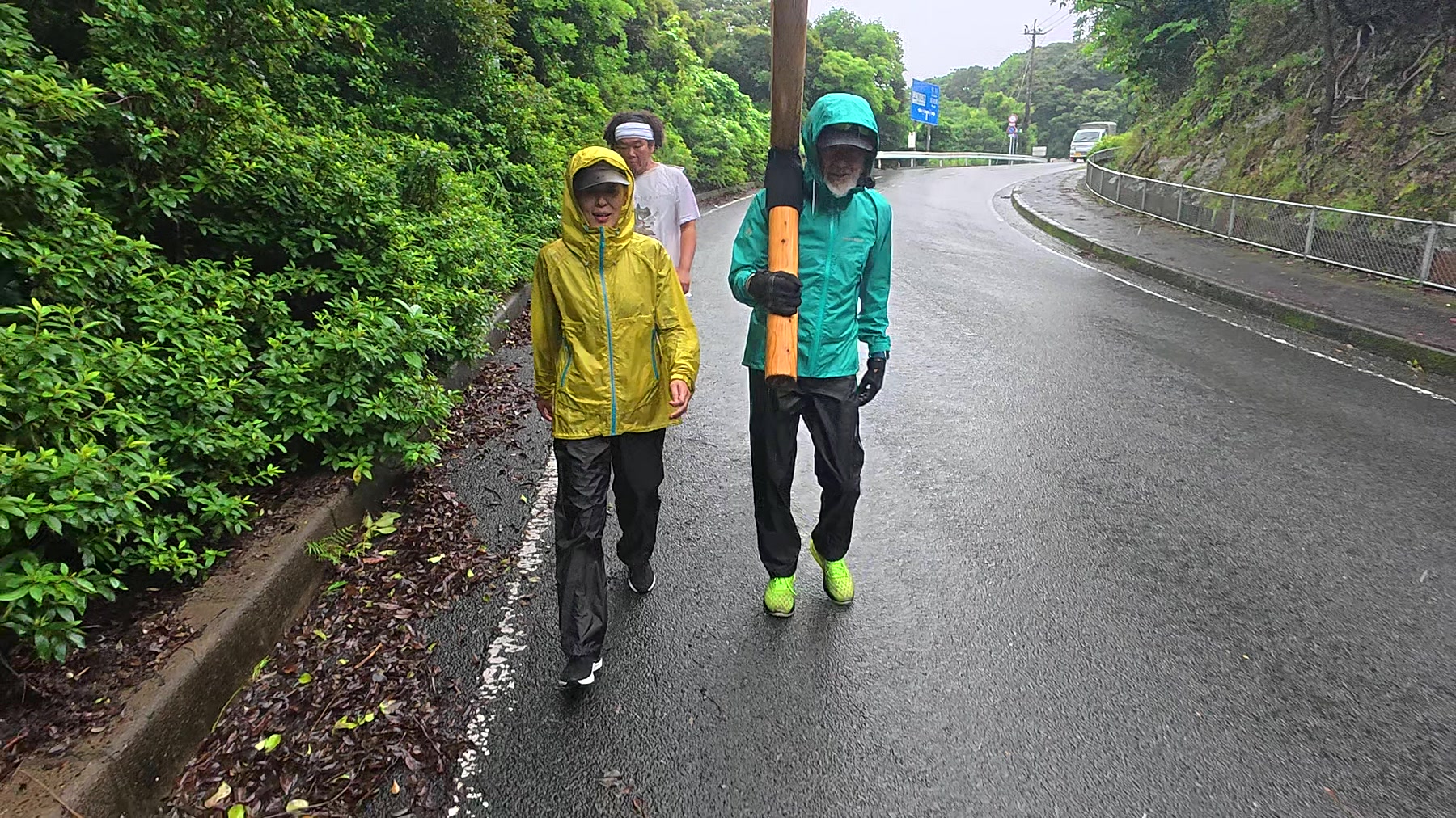 雨の上五島の道を十字架とともに歩く参加者たち