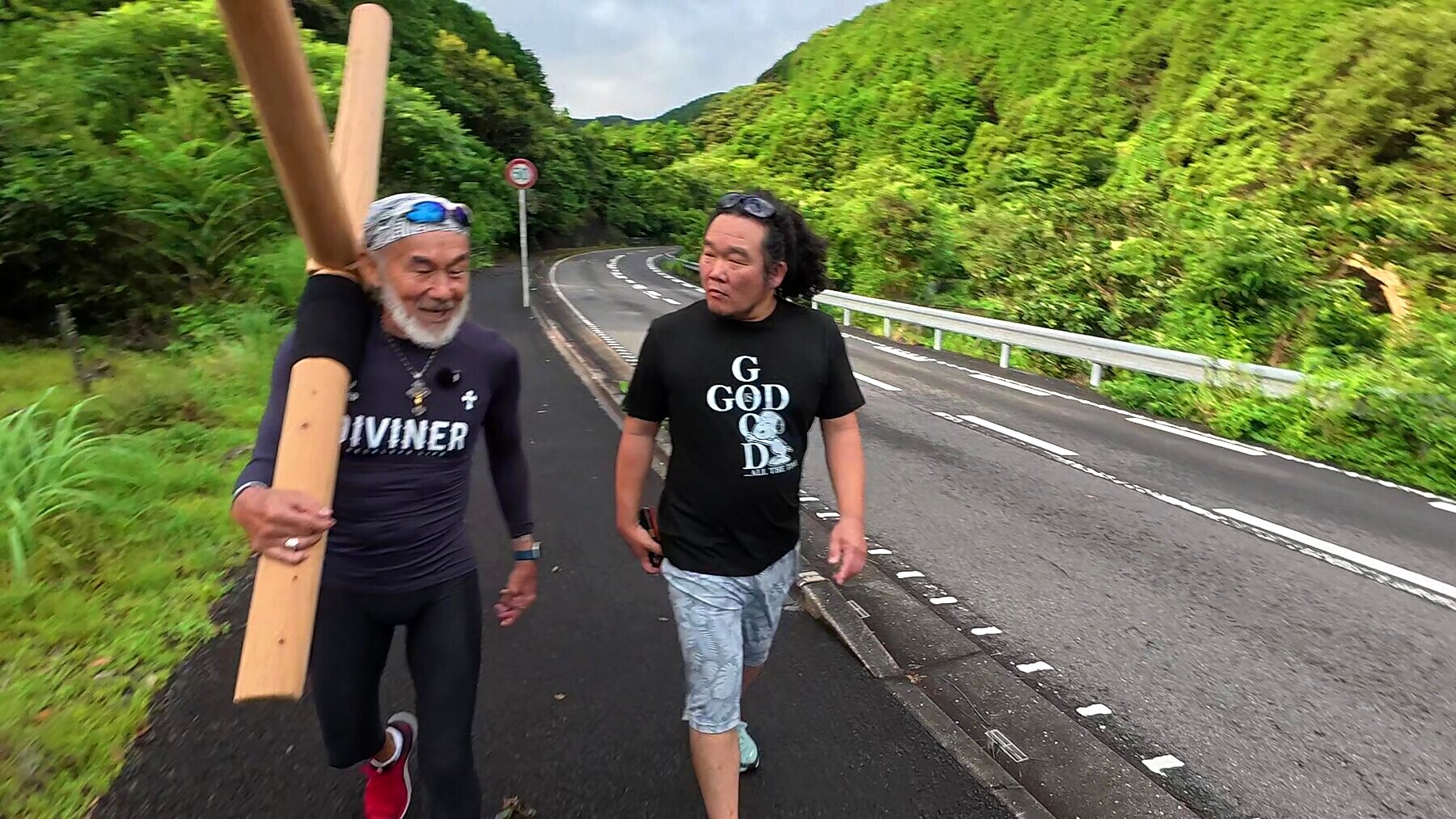 奈良尾からの道をアーサー先生と参加者が十字架とともに歩き出す場面