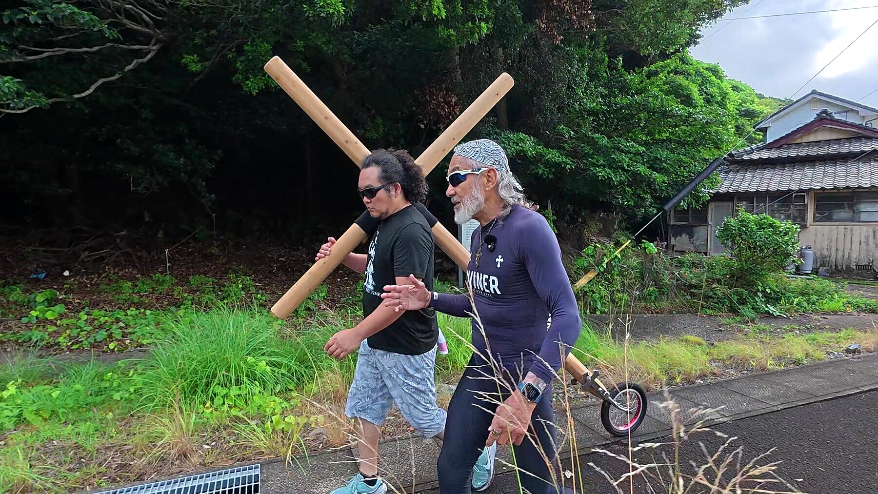緑に囲まれた上五島の道を十字架とともに歩くアーサー先生と参加者