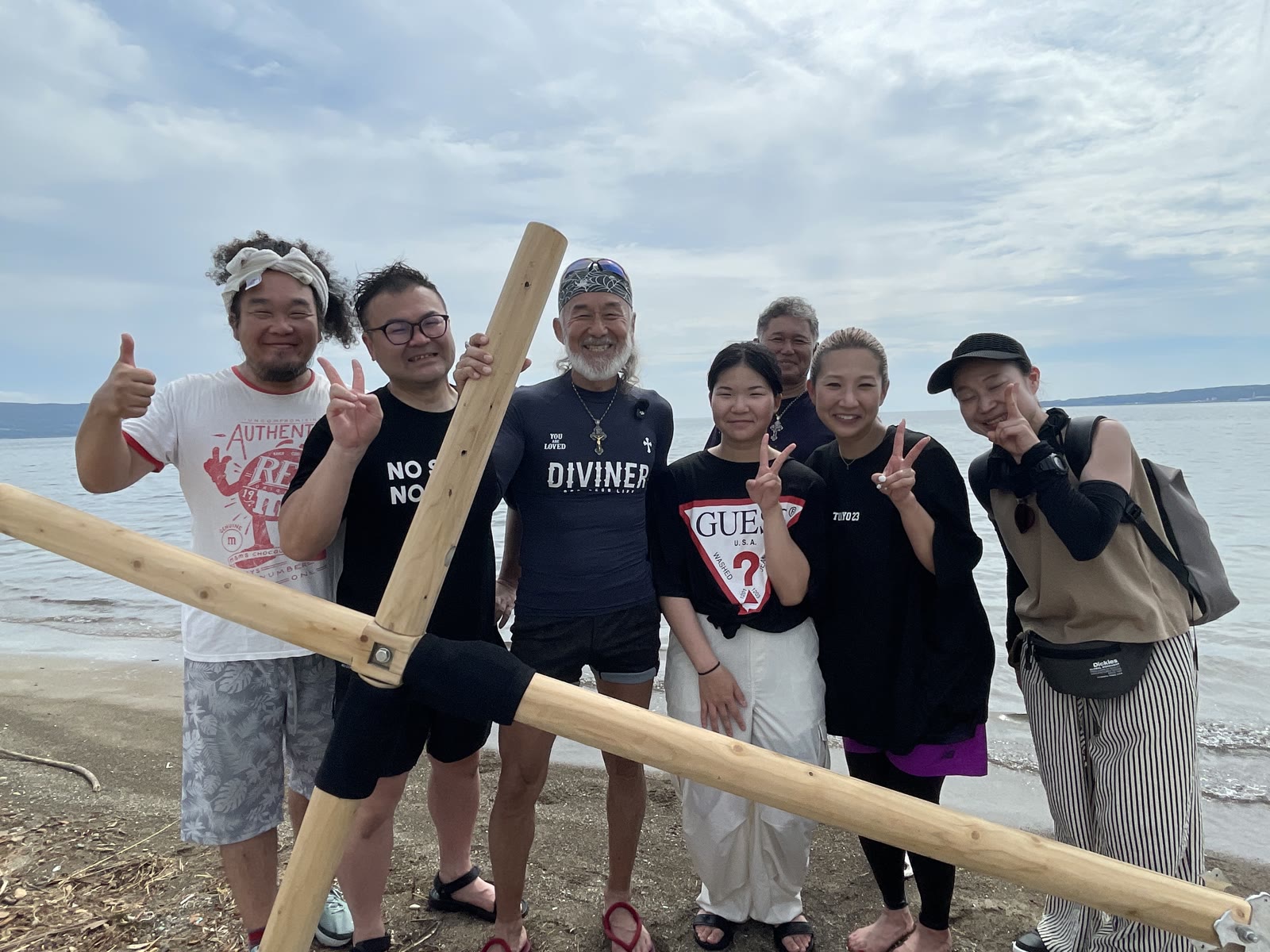 洗礼後、海辺で十字架を囲む片山さんご一家、アーサー・ホーランドと参加者たち